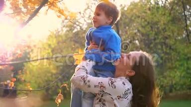 妈妈抱着一个孩子玩，把他抱起来。阳光穿过孩子。欢乐的笑声